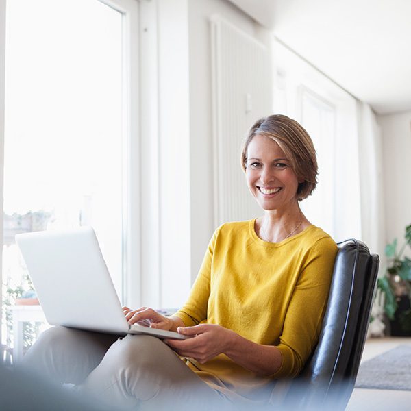 Woman smiling at her computer learning about on page SEO vs off page SEO