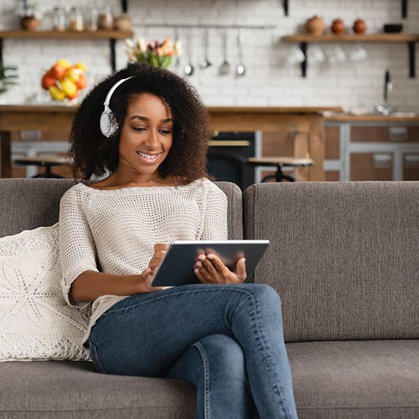 Woman on the couch listening to a podcast called everything you need to about a podcast manager