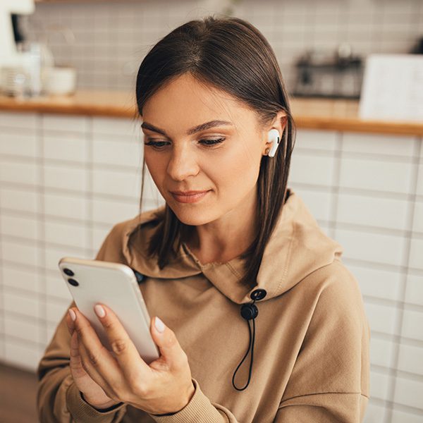 Woman on her phone listening to a podcast about how to promote a podcast
